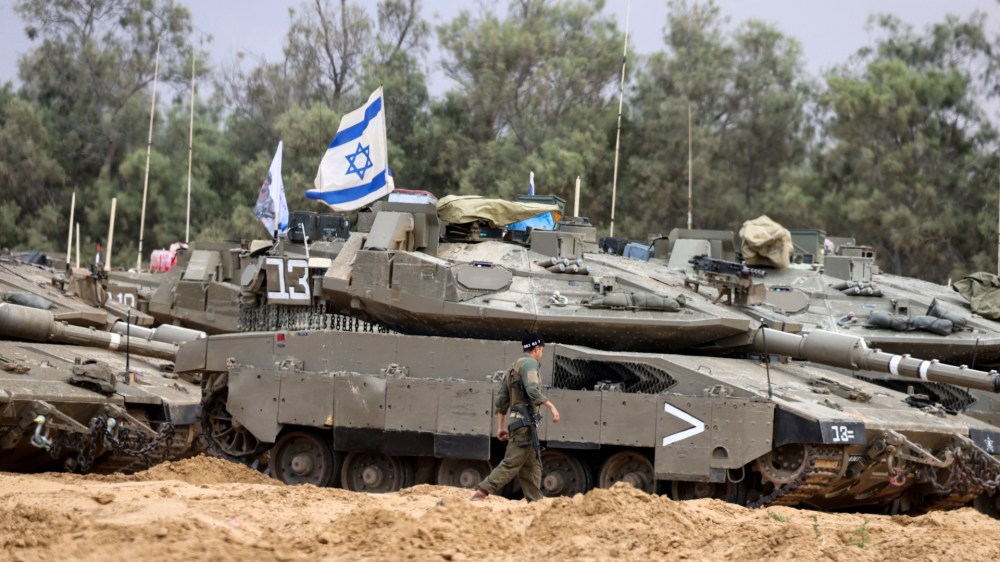 An Israeli soldier walks near tanks deployed at a position near Israel's border with the Gaza Srip on May 4, 2025. Israel was issuing orders to call up tens of thousands of reservists ahead of an expanded offensive in Gaza, Israeli media reported on May 3, as Prime Minister Benjamin Netanyahu attacked truce mediator Qatar. (Photo by Menahem KAHANA / AFP) (Photo by MENAHEM KAHANA/AFP via Getty Images)